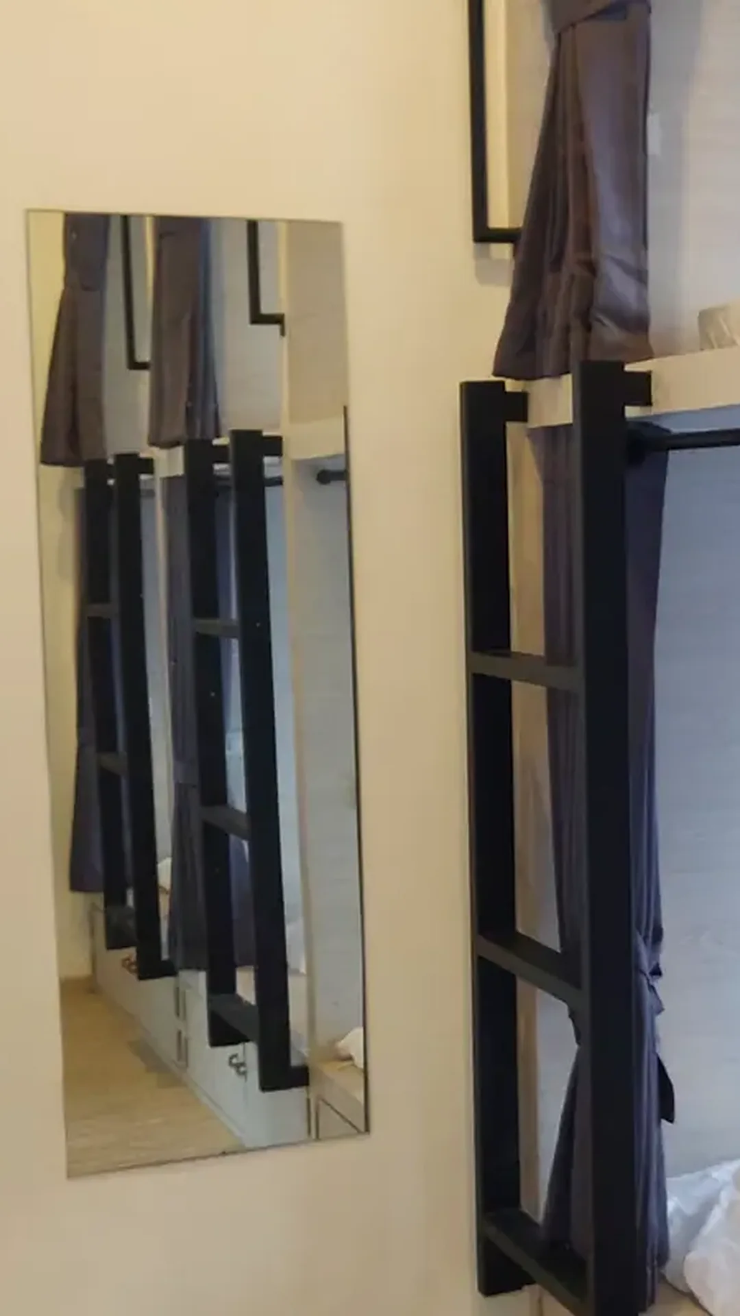 A full-length mirror in a dorm at Nolo Hub Pai, beside pods one above the other, each with its own ladder and curtain