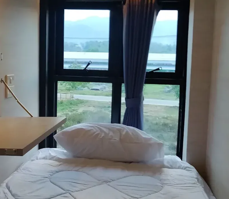 Sleep: a made bed in a pod, with a pillow and a window behind it